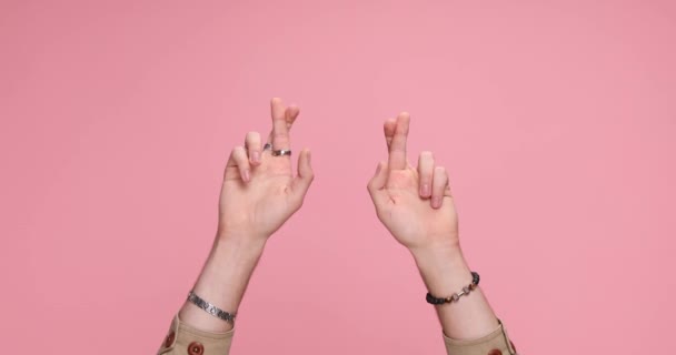 duas mãos segurando dedos cruzados para boa sorte no fundo rosa - Filmagem, Vídeo