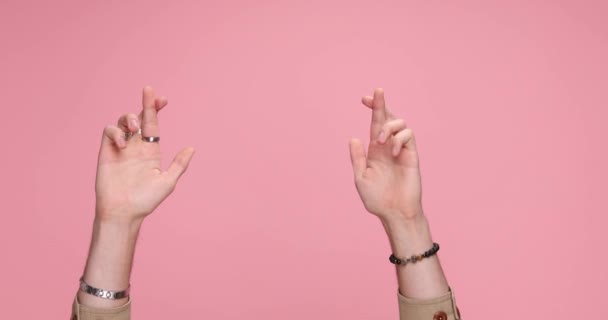 two hands crossing fingers the parting, giving a thumbs up on pink background - Imágenes, Vídeo