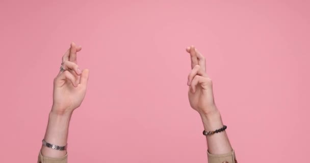 két kéz keresztbe ujjak majd tapsolnak rózsaszín háttér - Felvétel, videó