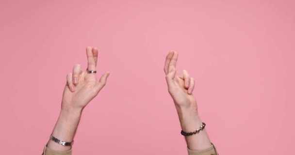 two hands crossing fingers, parting and giving a dislike on pink background - Video