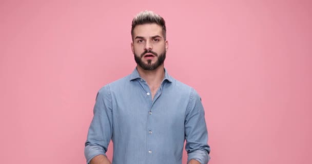 young casual man feeling angry, showing his fists, pointing his finger and sending a warning against pink background - Záběry, video