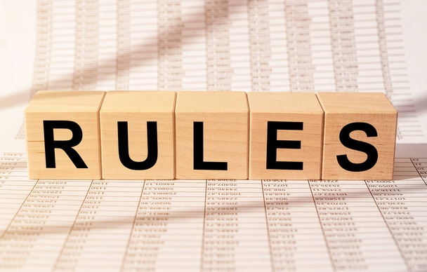 Rules word inscription on wooden cube on financial business documents - Foto, imagen