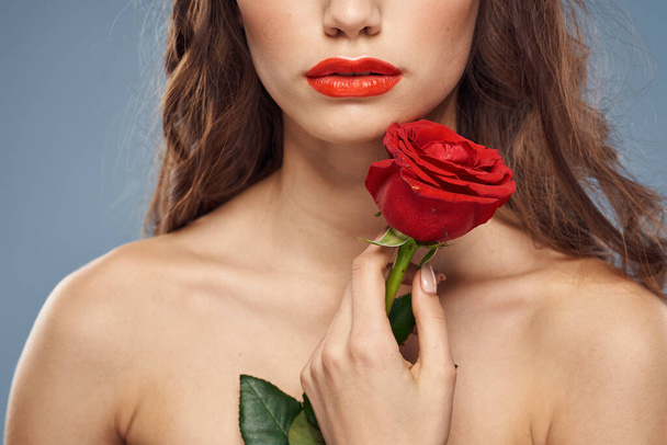 vrouw met een roos in haar handen naakt schouders avond make-up rode lippen - Foto, afbeelding