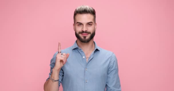 young casual guy showing his index finger at the camera on pink background - Footage, Video