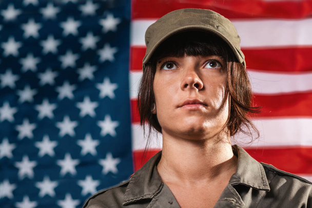 USA viering. Portret van een vrouwelijke soldaat, tegen de achtergrond van de Amerikaanse vlag. - Foto, afbeelding