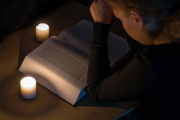 Modlící se dívka nad biblí ve světle svíček - Fotografie, Obrázek