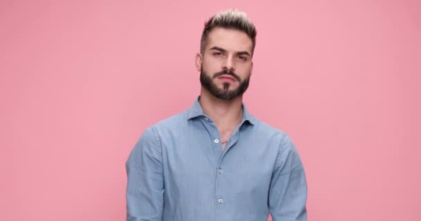 young casual man pointing at the camer and expanding his smile, giving a thumbs up on pink background - Materiaali, video