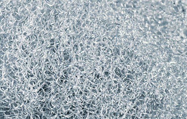 Heap of spiral twisted metal chips of alu alloy in silver-blue toned background. Abstract texture of shiny dural swarf tangle. Closeup of metallic waste. Turning by-product. Machining in metalworking. - Foto, Imagen