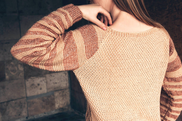 Young beautiful woman in a cozy beige sweater spends time outdoors - Photo, Image