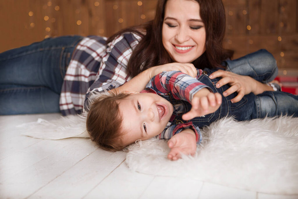 happy little son with mother lying on floor near Christmas boxes in apartment  - Foto, immagini