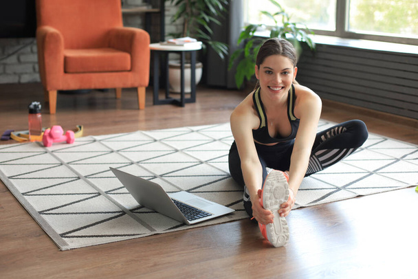 Fitness bella donna magra facendo esercizi di stretching fitness a casa in soggiorno. Rimanere a casa attività. Sport, stile di vita sano - Foto, immagini
