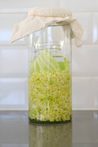 Sauerkraut fein geschnitten Rohkraut fermentiert von verschiedenen Milchsäurebakterien in einem Glas auf der heimischen Küchentheke. - Foto, Bild