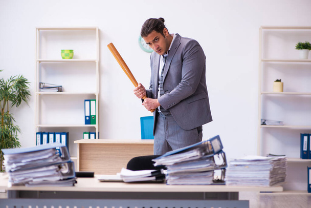 Young employee angry with excessive work holding baseball bat - Φωτογραφία, εικόνα