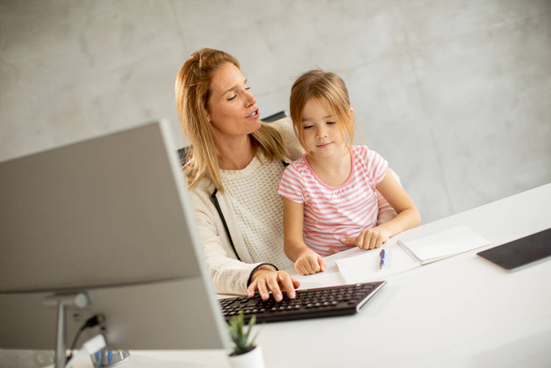 Working mother with her cute daughter in the office - Фото, изображение