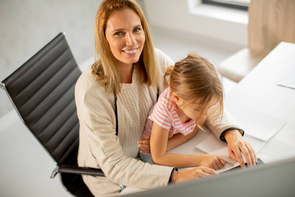 Η εργαζόμενη μητέρα με την χαριτωμένη κόρη της στο γραφείο - Φωτογραφία, εικόνα