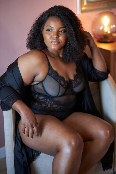 beautiful african plus size model sits on chair at home, have rest - Zdjęcie, obraz