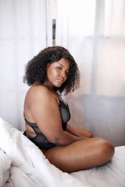 plump african woman in lingerie sits on bed in the morning - Fotó, kép