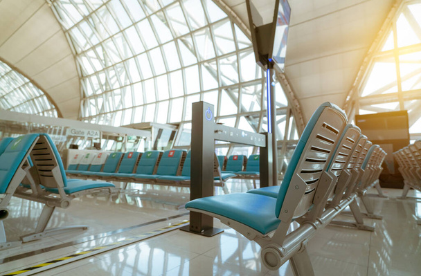 Selectieve focus op stoel in vertrekhal op luchthaventerminal. Afstand voor een stoel afstand te houden om coronavirus en passagiers sociale afstand te beschermen. Glazen raam bij luchthaven gate terminal. - Foto, afbeelding
