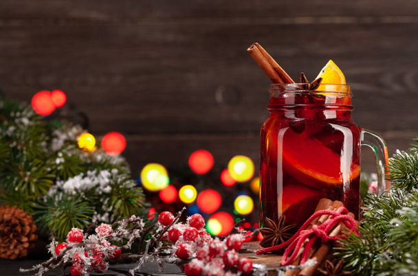 Χριστουγεννιάτικο κρασί με μπαχαρικά και εσπεριδοειδή, χριστουγεννιάτικο δέντρο και φώτα bokeh - Φωτογραφία, εικόνα