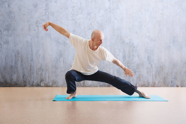 man praticing tai chi chuan in the gym. Chinese management skill Qi's energy. WU-SHU. Man practicing yoga. - Фото, зображення