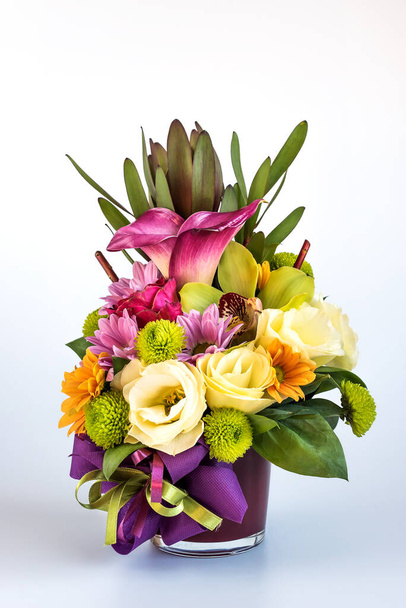 Disposizione dei fiori in un vaso viola su sfondo bianco. - Foto, immagini