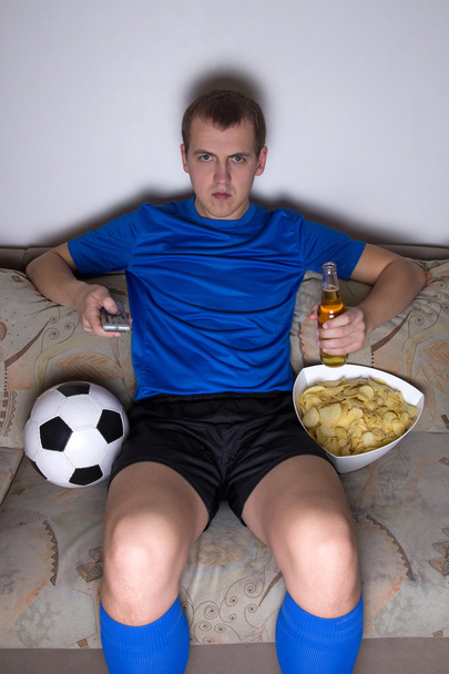 hombre aburrido en el fútbol uniforme sentado en la sala de estar y ver - Foto, imagen