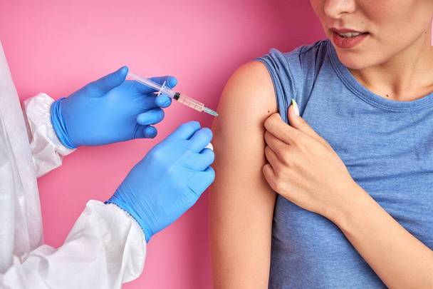 confident doctor with syringe doing injection vaccine,flu,influenza in the shoulder of woman - Fotó, kép