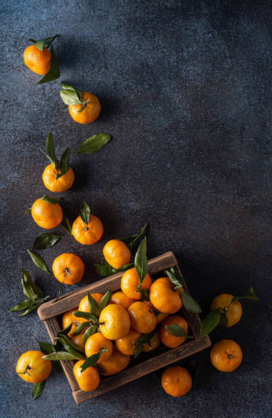 ripe tangerines with leaves in a wooden box, top view - Photo, image