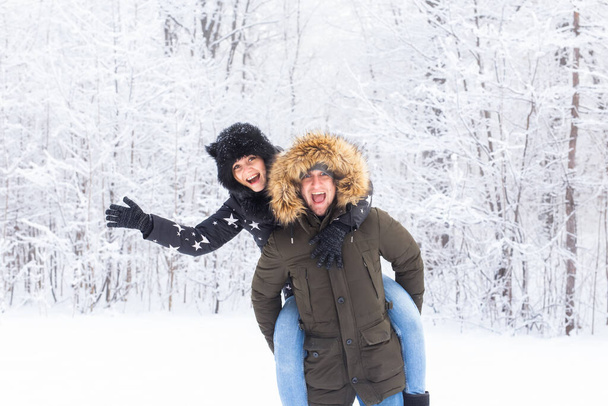 Portrait of happy young couple in winter park with their friend behind - 写真・画像