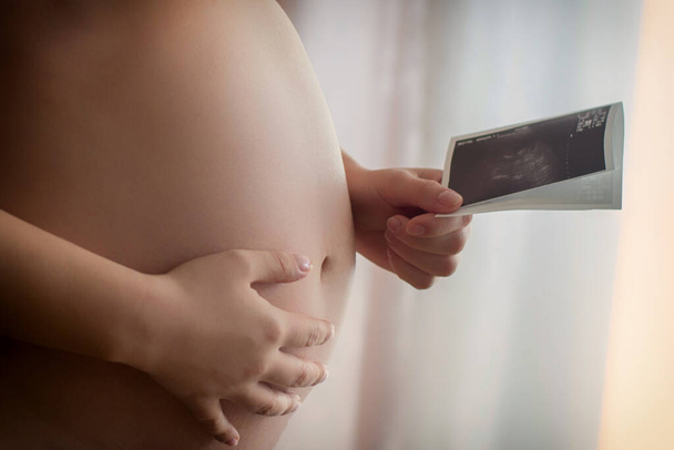 Terhes nő kezében ultrahang fotó gyermeke - Fotó, kép