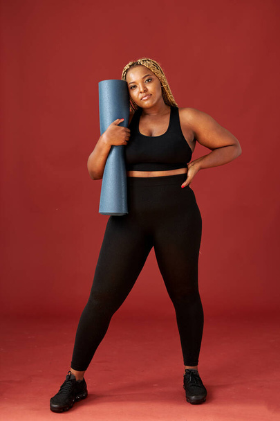 confident black female in sportive wear going to do yoga execises on mat - 写真・画像