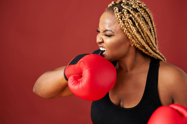 attractive young fat black sports fitness boxer woman in sportswear working out isolated on red background - Φωτογραφία, εικόνα