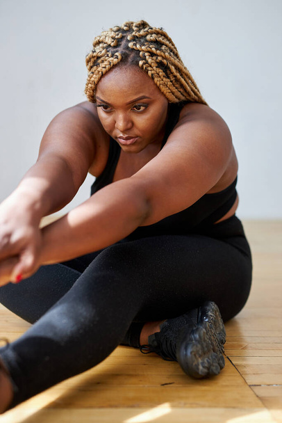 chubby african american woman do exercises sitting on the floor - Foto, imagen