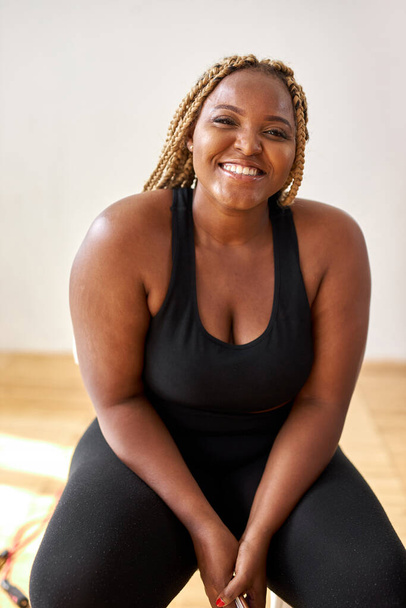 plump, plus size african american woman in sportswear sit looking at camera - Фото, зображення