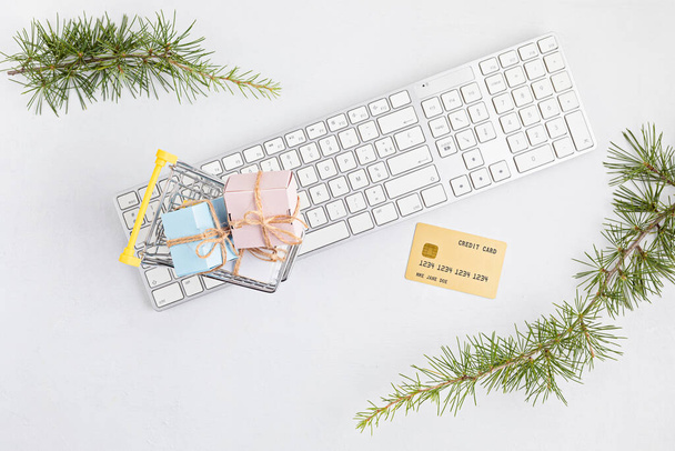 Online kerstwinkelconcept met geschenkdozen, toetsenbord en gouden kredietkaart. Bovenaanzicht, plat, model - Foto, afbeelding