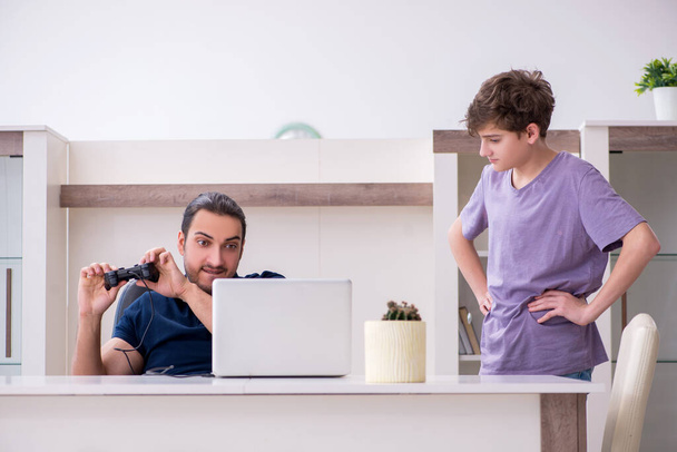 Młody ojciec i uczeń grający w gry komputerowe w domu - Zdjęcie, obraz