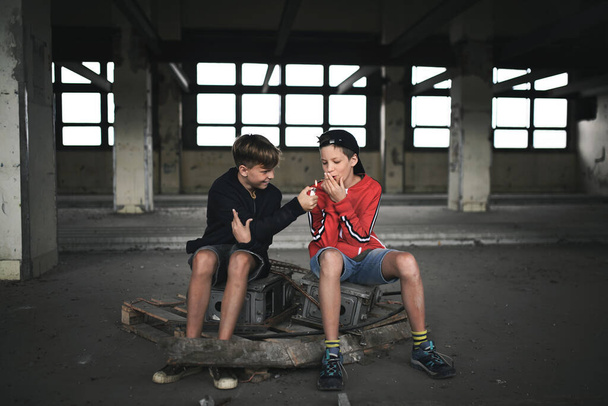 Група хлопчиків-підлітків в приміщенні в покинутій будівлі, куріння сигарет
. - Фото, зображення