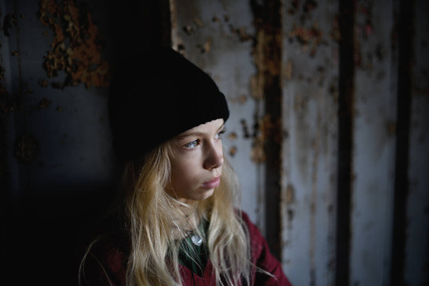 Egy szőke tinédzser lány portréja, aki egy elhagyatott épületben áll.. - Fotó, kép