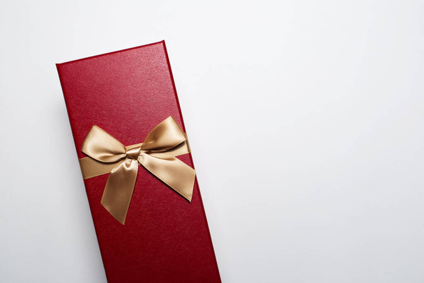コピースペースと白い背景に隔離された黄金の弓と赤い色のクリスマスギフトボックスのクローズアップ. - 写真・画像