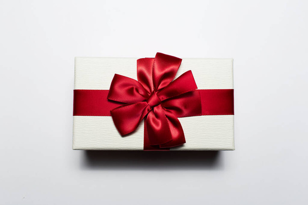 Κοντινό πλάνο των Χριστουγέννων κουτί δώρου λευκό χρώμα με κόκκινο τόξο, απομονώνονται σε λευκό φόντο. - Φωτογραφία, εικόνα
