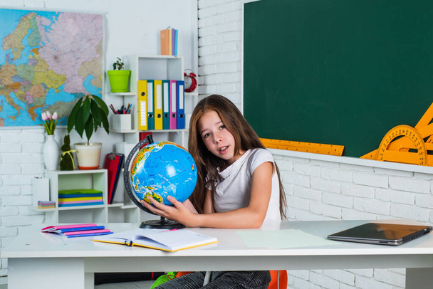 find the location. cheerful kid learning geography. modern education. knowledge day. child pupil use globe. girl is college student. back to school. teen girl work in classroom near blackboard - Фото, изображение