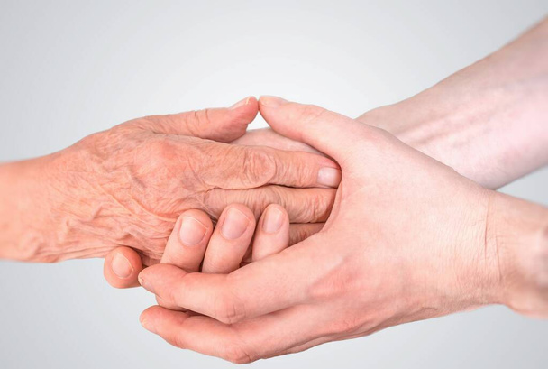 Der Mann hält die Hände der älteren Frau. Seniorenhilfe- und Betreuungskonzept. - Foto, Bild