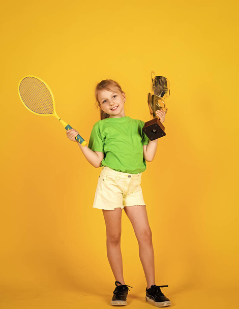 Sport is life. small girl hold championship cup and tennis racket. badminton game champion. Victory and win. Sport achievement. sport success concept. happy childrens day. happy childhood - Foto, Imagem