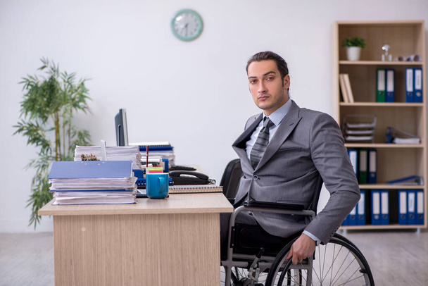 Joven empleado en silla de ruedas en el lugar de trabajo - Foto, Imagen