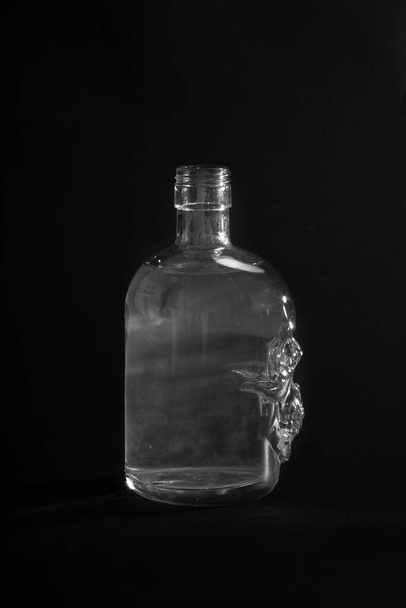 Empty skull bottle on black background - Фото, зображення