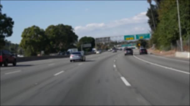 Jazda autostradą międzymiastową w Los Angeles, Kalifornia USA. Nieostry widok z przedniej szyby samochodu na ruchliwej autostradzie międzystanowej. Zamazane przedmieścia wielokrotnego podjazdu. Kamera wewnątrz auto w LA - Materiał filmowy, wideo