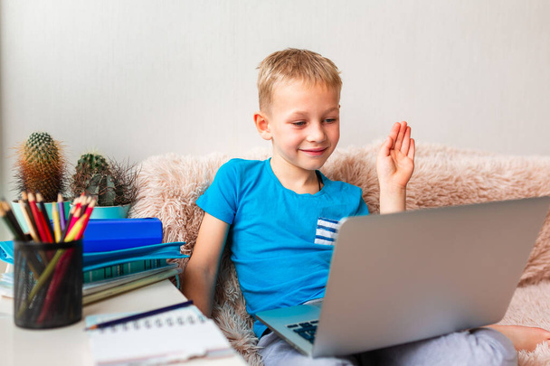 Little young school boy working at home with a laptop and class notes studying in a virtual class. Distance education and learning, e-learning, online learning concept during quarantine - Zdjęcie, obraz