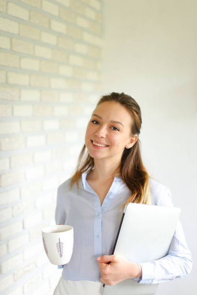 Portrait of young smiling girl standing with paper folder and coffee. - Φωτογραφία, εικόνα