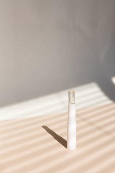 Белая экологическая гигиена помады в полосатой тени серый фон. - Фото, изображение