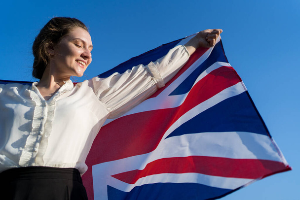 Patriot with the national flag of Great Britain. Independent woman smiles and rejoices - Zdjęcie, obraz